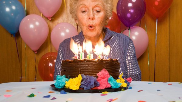 задувает свечи на торте